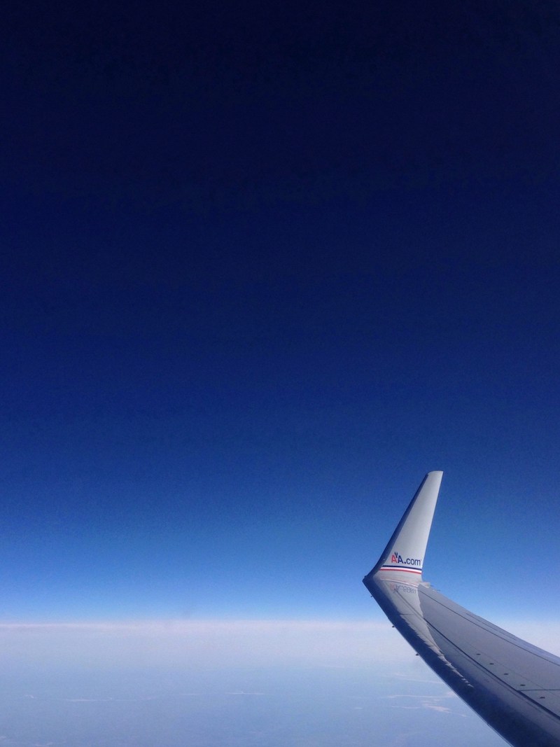 Airplane wing against backdrop of clouds and blue sky