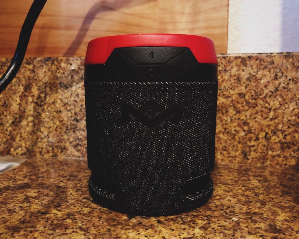 An up close shot of a bluetooth speaker on a granite countertop.