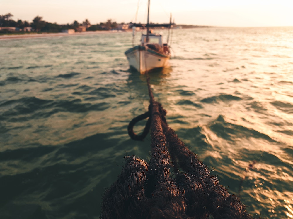 Boat on water in background pulling nets in foreground. Photo by Angel Abraham Cab Gonzalez on Unsplash.