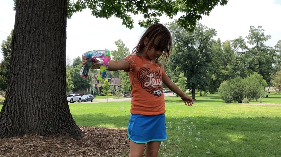 Young human in park playing with a bubble maker.