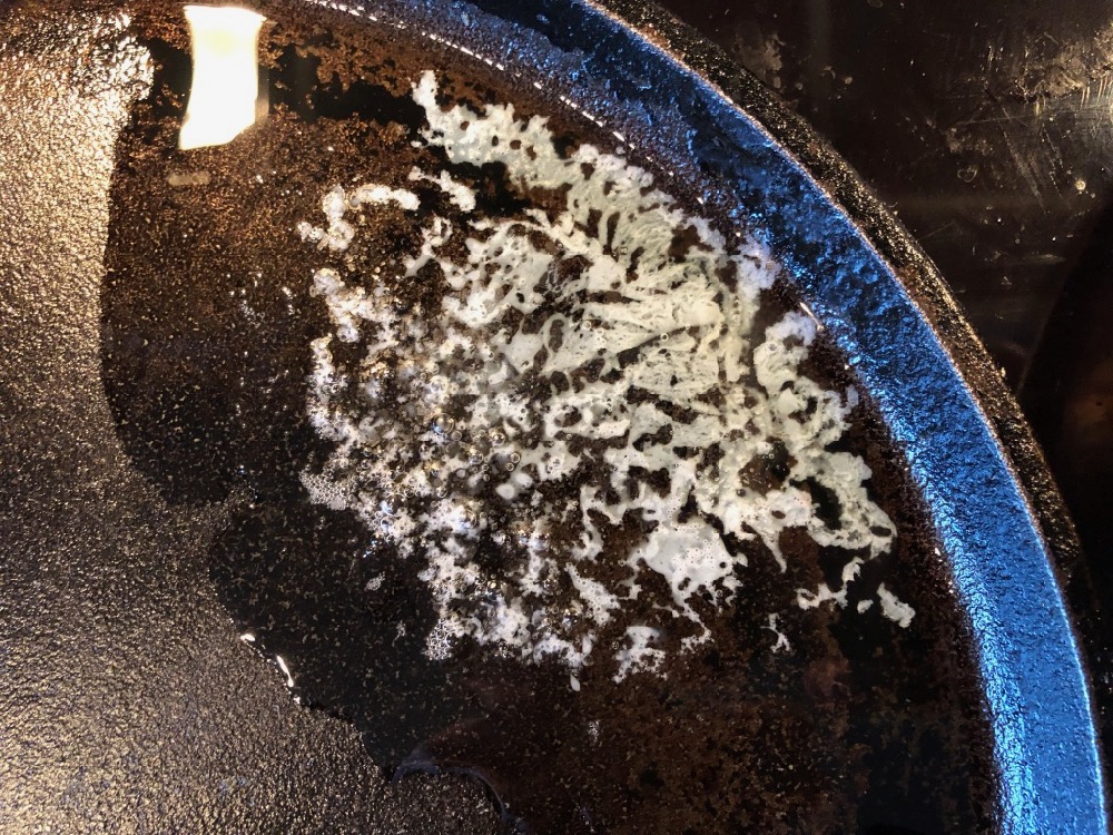 Close-up photo of butter melting on a cast-iron pan.