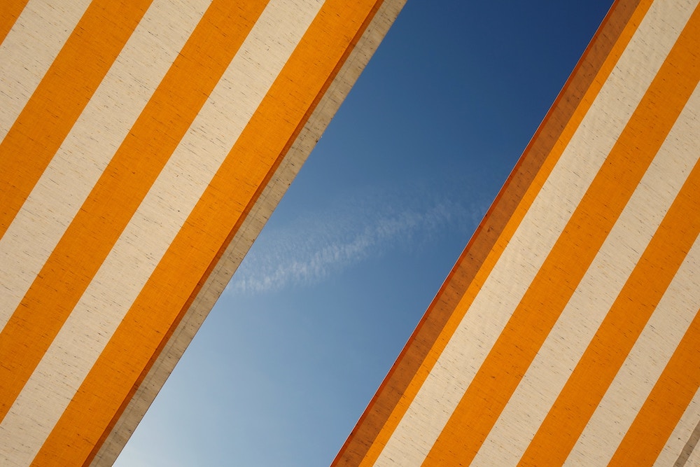 Yellow and white fabric, lit by the sun, with blue skies and light clouds in the background.