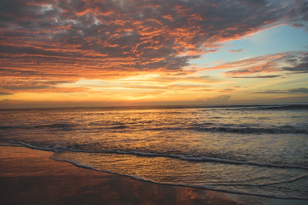 sunrise over the ocean. clouds are pink and orange.