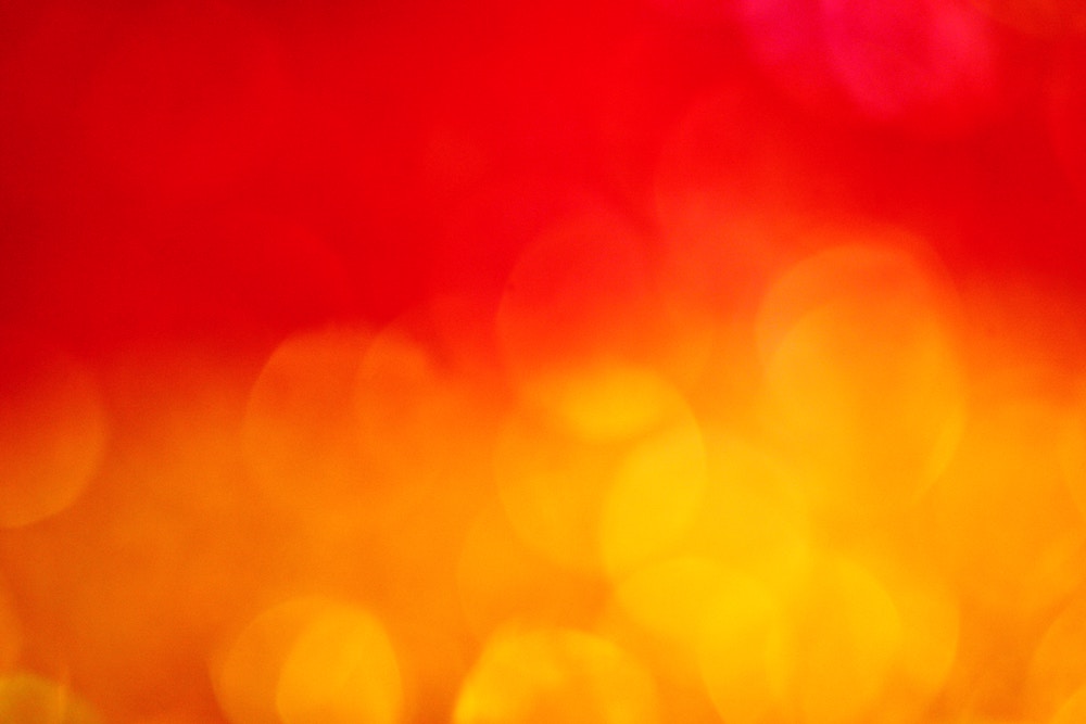 Bokeh-like circles of oranges and yellows melding over a red background.