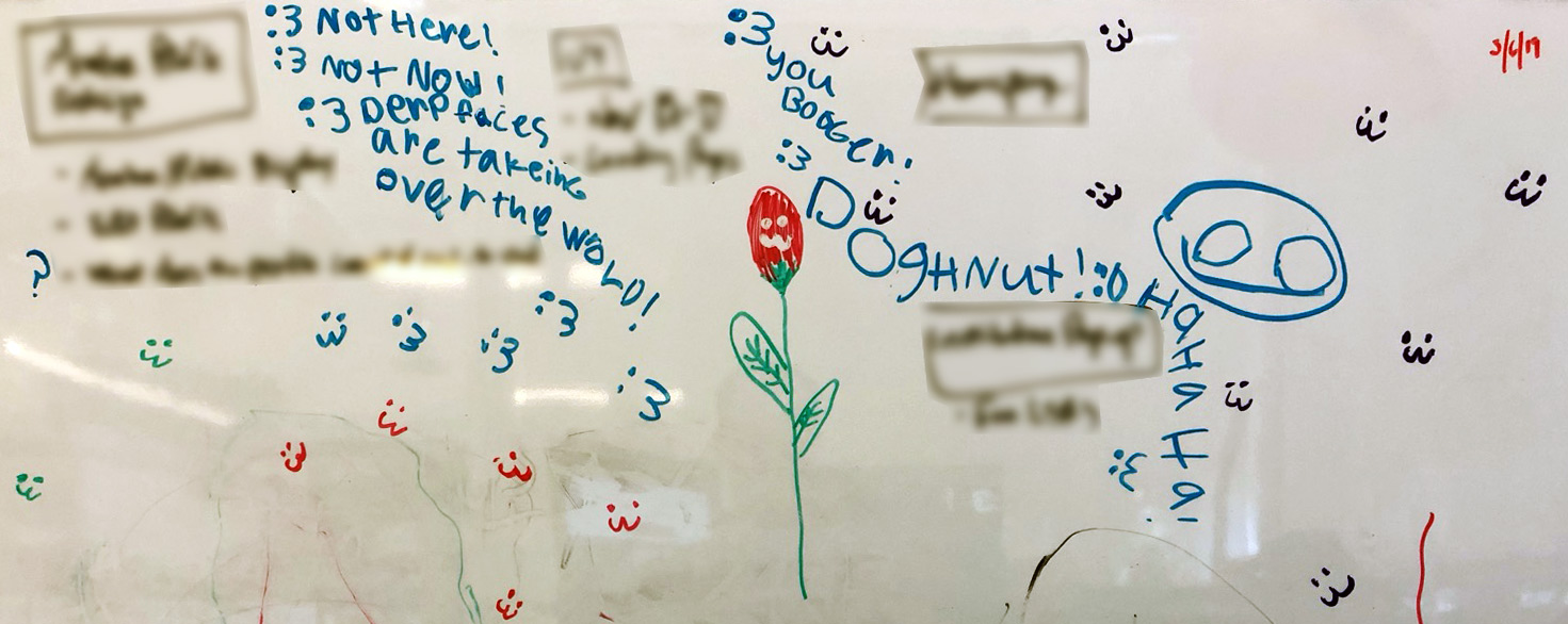 Children's writings and drawings in different color marker on part of a whiteboard.